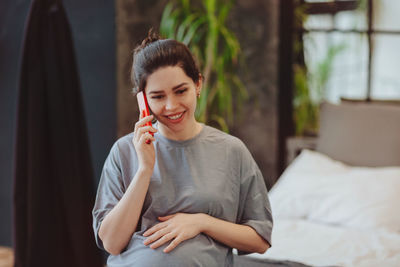 Young woman drinking while lying on bed at home