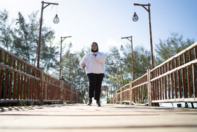 Full length of young man standing on footbridge