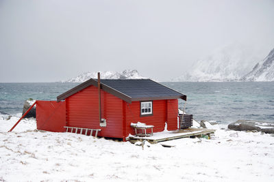 Houses by sea against sky during winter