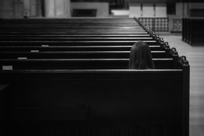 Rear view image of girl sitting in church facing alter 