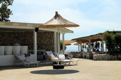 Chairs on table by swimming pool against sky