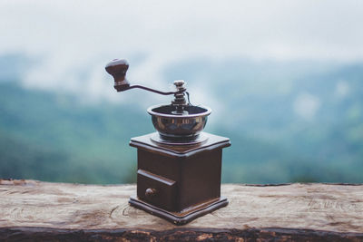 Close-up of coffee grinder on table against sky