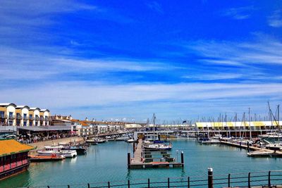 Boats in harbor against cloudy sky