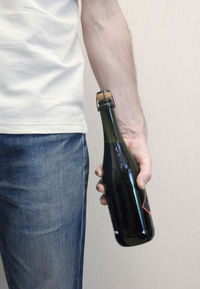 Midsection of man holding bottle