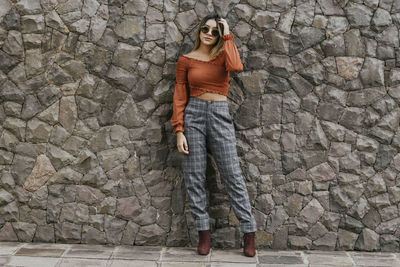 Woman standing against stone wall