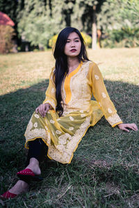 Beautiful young woman sitting on field