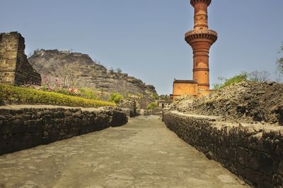 Footpath leading to built structure against clear sky