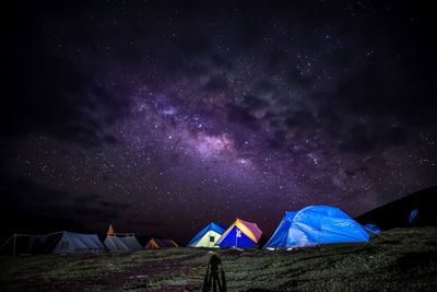 Tents on field against sky at night