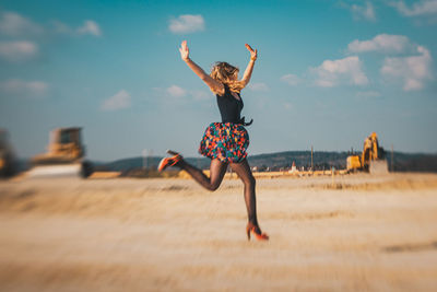 Rear view of woman jumping against sky