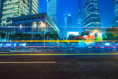 Light trails on city street by buildings at night