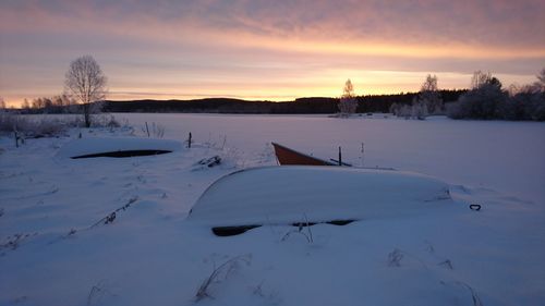 Scenic view of frozen landscape against sky at sunset