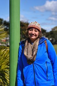 Portrait of smiling young woman against blue sky