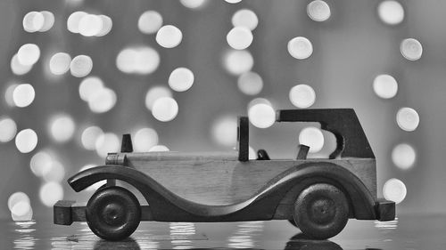 Close-up of wooden toy car on table against illuminated light