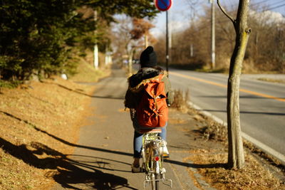 Rear view of girl riding bicycle on road