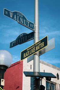 Low angle view of road sign against blue sky