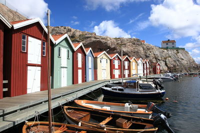 Boats moored in sea by houses against sky