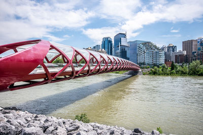 Bridge over river by buildings against sky