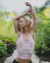 Young woman stretching against plants at park