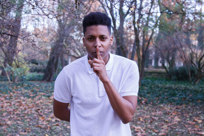 Portrait of young man with finger on lips over field