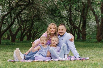 Happy beautiful family sitting on the beach in summer in the park