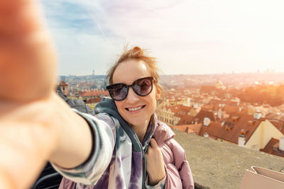 Portrait of young woman wearing sunglasses while standing against sky