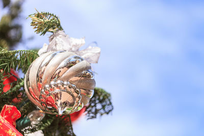 Low angle view of bauble hanging on christmas tree against sky