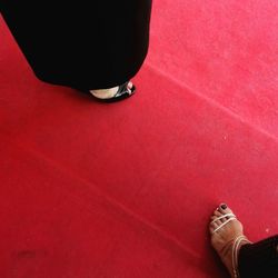 Low section of women standing on red carpet