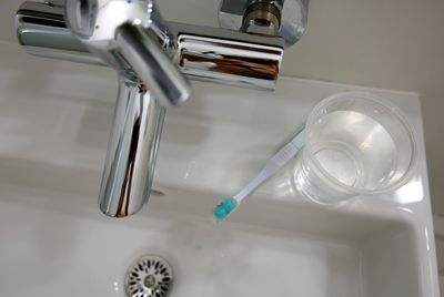 High angle view of toothbrush and water glass on bathroom sink