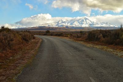 Road by snowcapped mountains against sky