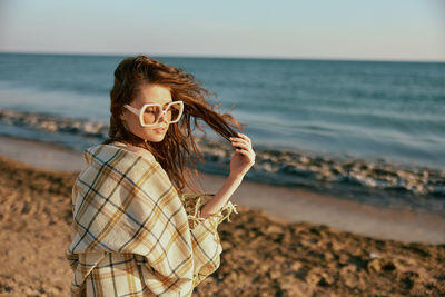 Portrait of young woman standing at beach