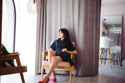 Young woman sitting on table at home