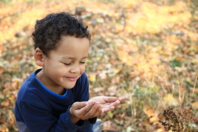 Close-up of boy with autumn leaves