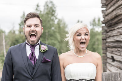 Portrait of smiling bride and groom with mouth open in yard