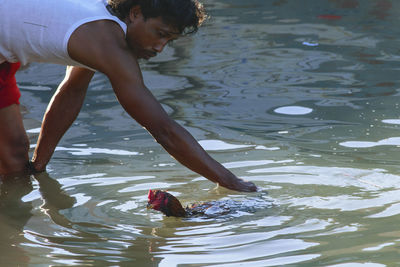 Man catching rooster while standing in water