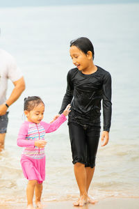 Wet siblings walking at shore