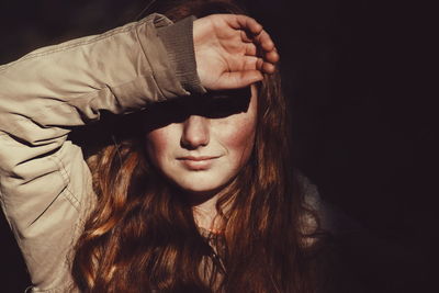 Close-up portrait of young woman against black background