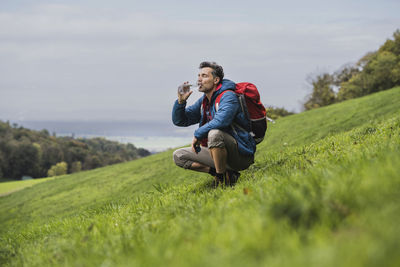 Man drinking water through bottle on grass