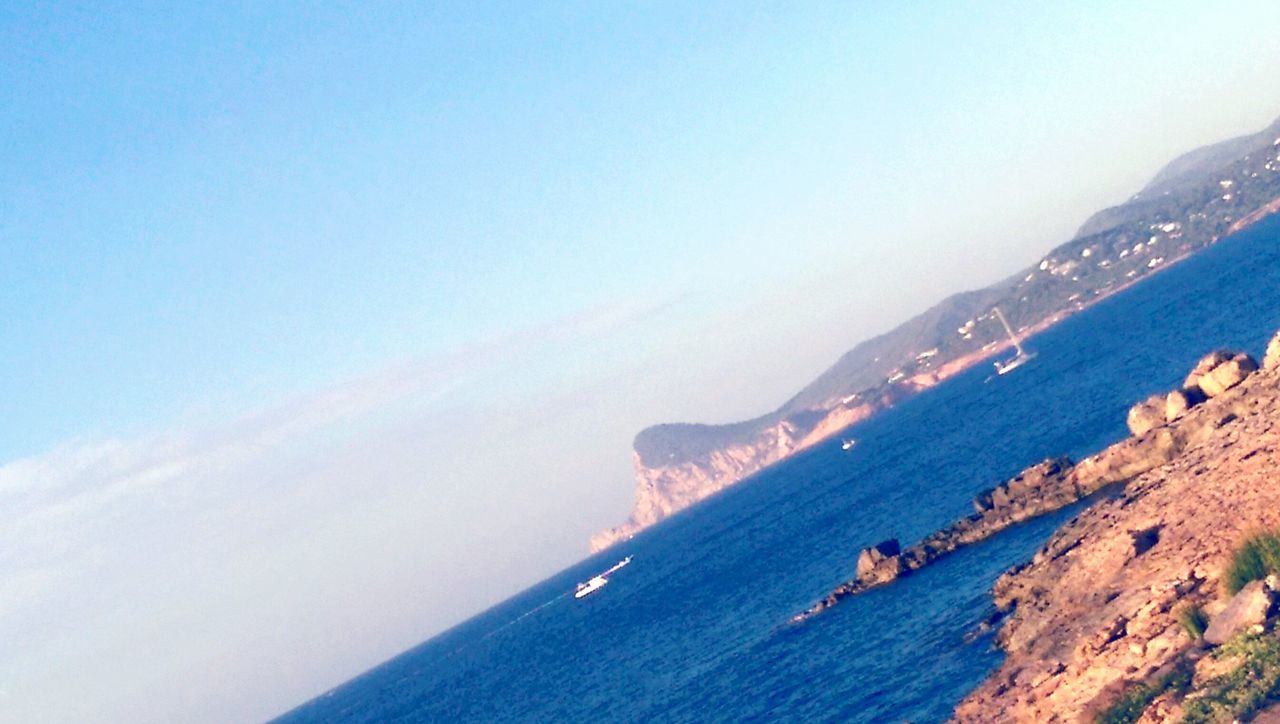 SCENIC VIEW OF SEA WITH MOUNTAIN RANGE IN BACKGROUND