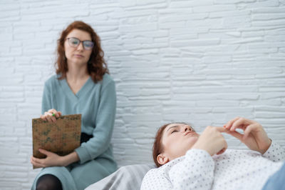 A middle-aged woman lies on a couch and talks to a psychologist