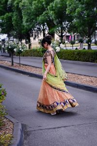 Full length of young woman wearing traditional clothing walking on road