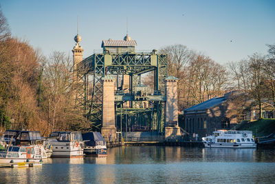 View of buildings by river against sky