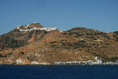 Scenic view of sea and mountains against clear blue sky