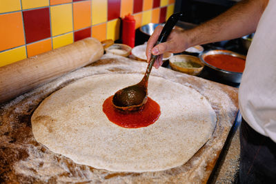 Close-up of man preparing pizza in kitchen at restaurant