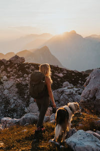 Man with dog standing on mountain against sky