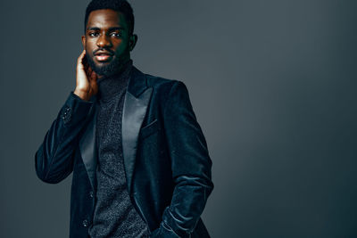 Young man standing against black background