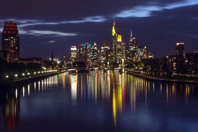 Illuminated skyscrapers reflection in main river against sky at night