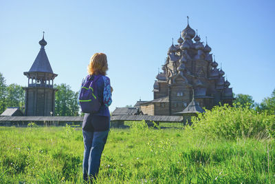 Rear view of woman standing on field against sky