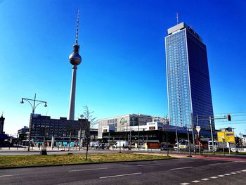 View of communications tower and buildings against blue sky