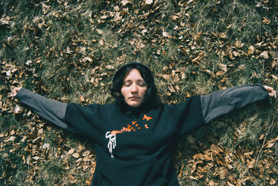 Portrait of young woman standing by leaves during autumn