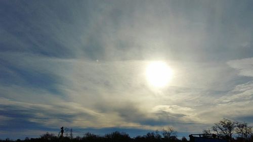 Low angle view of trees against cloudy sky